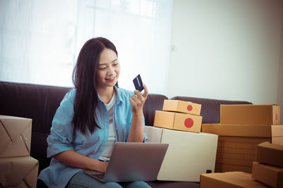 Young woman using phone while sitting in box