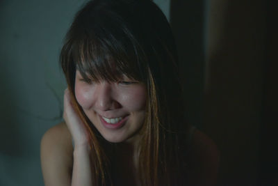 Close-up of young woman with long hair smiling at home