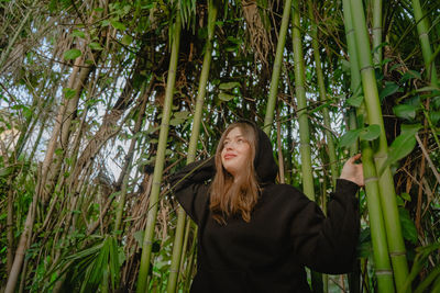 Portrait of young woman standing amidst plants