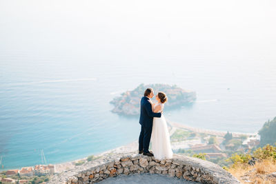 Rear view of couple kissing against sea