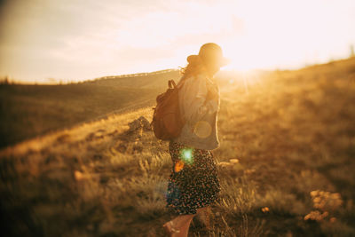 Side view of woman walking on land against sky