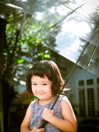 Portrait of smiling girl with umbrella standing on footpath