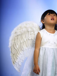 Cute girl looking away while standing against white background