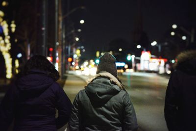 Rear view of man on illuminated street in city at night