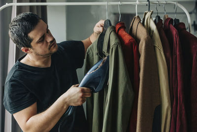 Man steam ironing clothes on rack