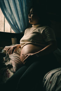 Side view of woman relaxing on bed at home