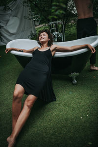 Beautiful woman sitting on grass against plants