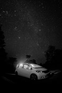 Cars on illuminated street against star field at night