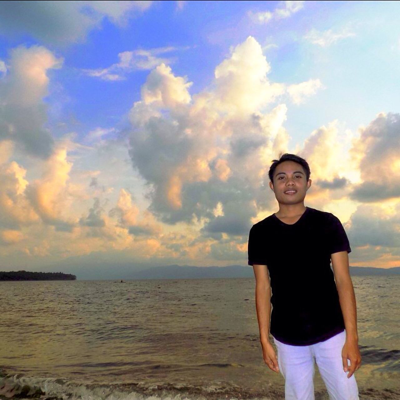 sky, lifestyles, person, sea, leisure activity, water, casual clothing, beach, standing, looking at camera, portrait, young adult, cloud - sky, three quarter length, shore, horizon over water, beauty in nature, scenics