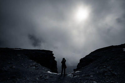 Low angle view of man standing on cliff against sky