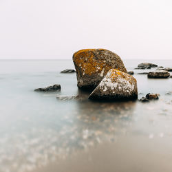 Close-up of rocks on sea against sky