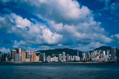 View of city at waterfront against cloudy sky