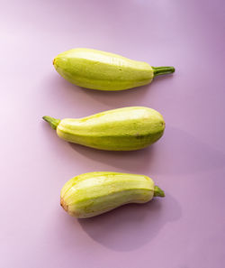 Three green zucchini on a soft purple background