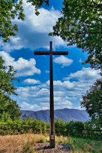 Cross on field against sky