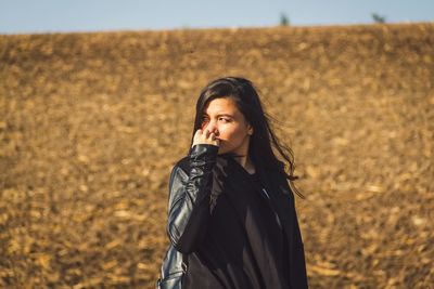 Portrait of young woman standing on field