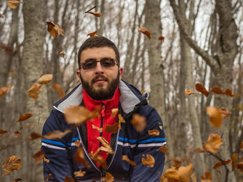 Portrait of smiling man standing in forest during winter