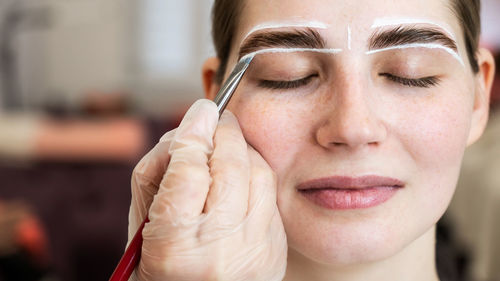 Close-up of young woman applying make-up