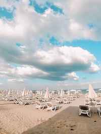 Deck chairs on beach against sky