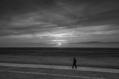 Side view of man walking on field against sky