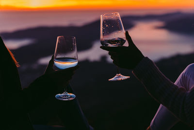 Cropped hands holding wine during sunset