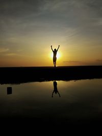 Silhouette man standing in water at sunset