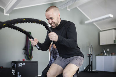 Man exercising with ropes in gym