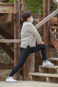 Full length of woman wearing mask exercising by steps