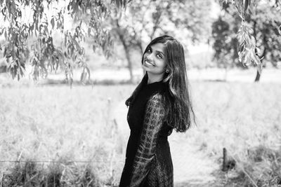 Portrait of smiling young woman standing on land