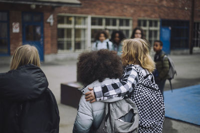 Boy walking with arm around friend in school campus