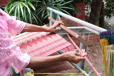 Midsection of woman holding pink while sitting in yard