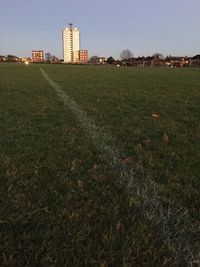 Scenic view of field against sky in city