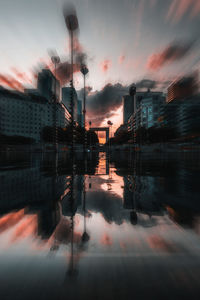 Digital composite image of silhouette buildings against sky at sunset