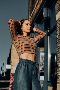 Young woman with arms raised standing in city