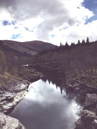 Scenic view of river against cloudy sky