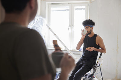 Gay couple having coffee break during flat renovation