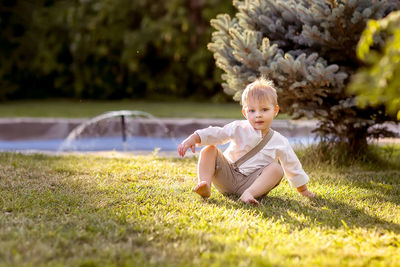 Full length of cute baby sitting on field