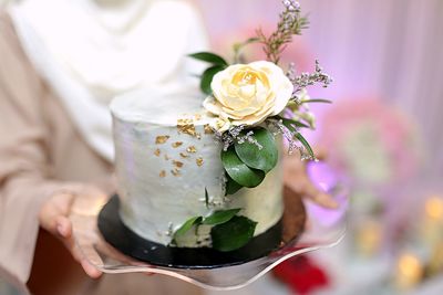 Midsection of bride holding wedding cake