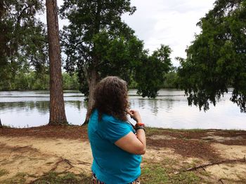 Rear view of woman standing at lakeshore against sky