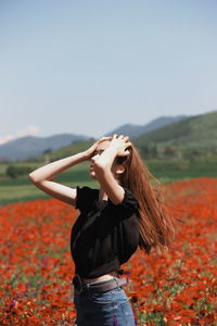 Young woman standing on field against sky