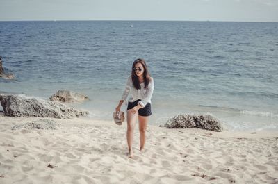 Full length portrait of young woman on beach