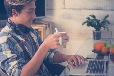 Midsection of man using mobile phone while sitting on table