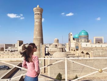 Woman standing by historic building against sky