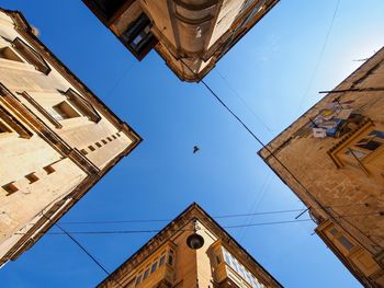 Directly below view of bird flying amidst buildings against sky