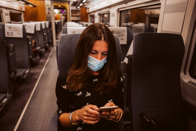 Young woman using mobile phone while sitting in bus