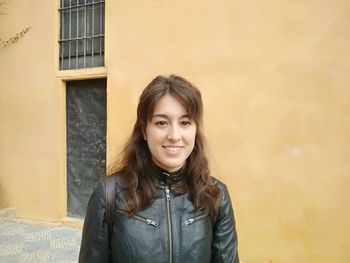 Portrait of smiling woman standing against wall
