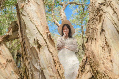 Portrait of a young woman against tree trunk