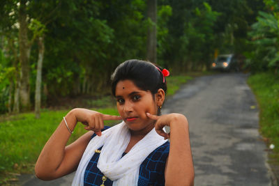 Portrait of beautiful young woman sitting on road