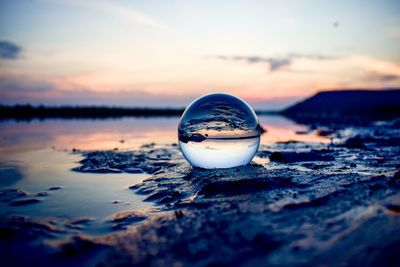 Close-up of ice crystals against lake during sunset