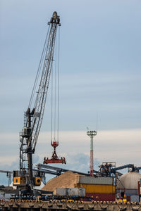 Cranes at commercial dock against sky