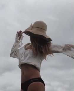 Woman wearing hat standing against sky